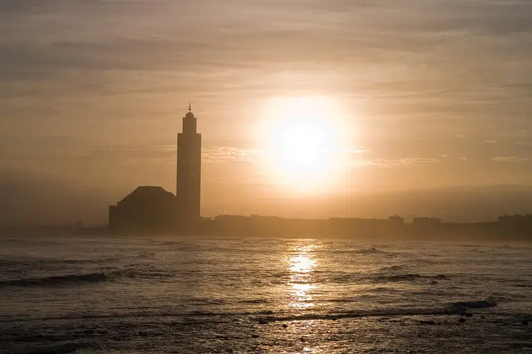 The Hassan II Mosque in Casablanca silhouetted against the setting sun over the Atlantic