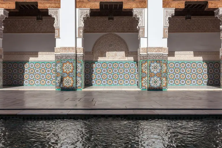 Zellige tilework and carved stucco around the courtyard pool of the Ben Youssef Madrasa in Marrakech